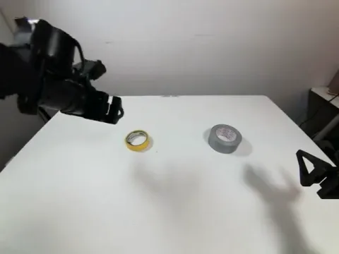 Robot gripper approaching the yellow tape roll from above